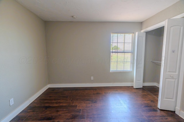 unfurnished bedroom featuring dark wood finished floors and baseboards