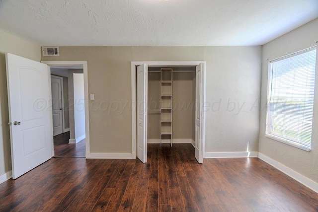 unfurnished bedroom featuring multiple windows, baseboards, and dark wood-style flooring