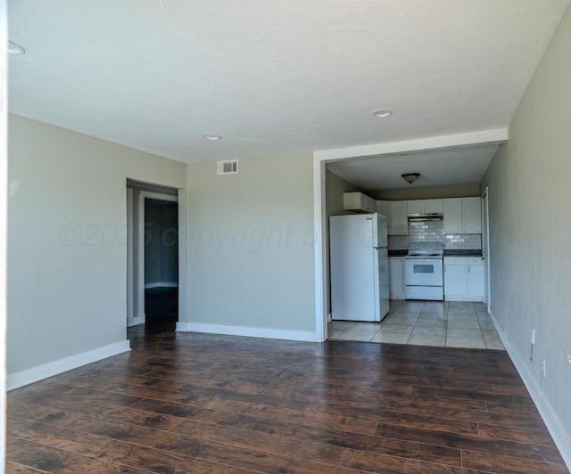 unfurnished living room with wood finished floors, baseboards, and recessed lighting