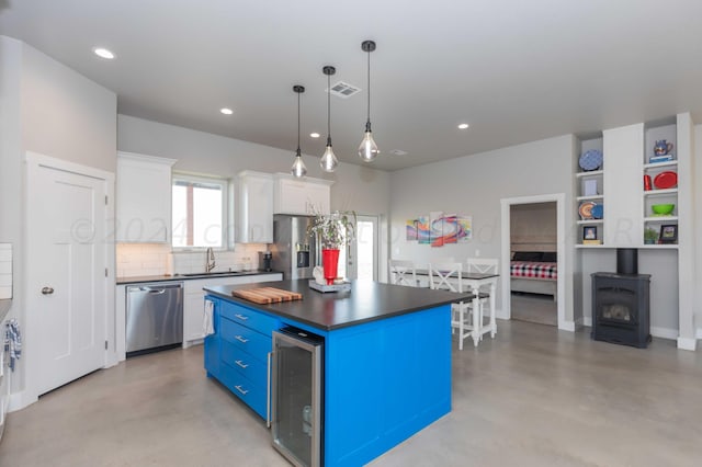 kitchen featuring stainless steel appliances, a center island, white cabinets, hanging light fixtures, and blue cabinetry