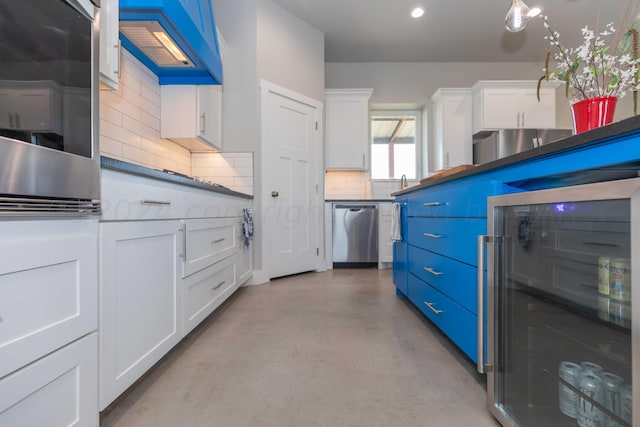 kitchen with white cabinets, appliances with stainless steel finishes, tasteful backsplash, and blue cabinets