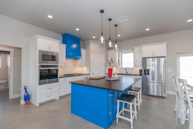 kitchen with stainless steel appliances, white cabinetry, decorative light fixtures, decorative backsplash, and a center island