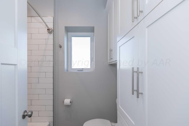 bathroom featuring toilet and a tile shower