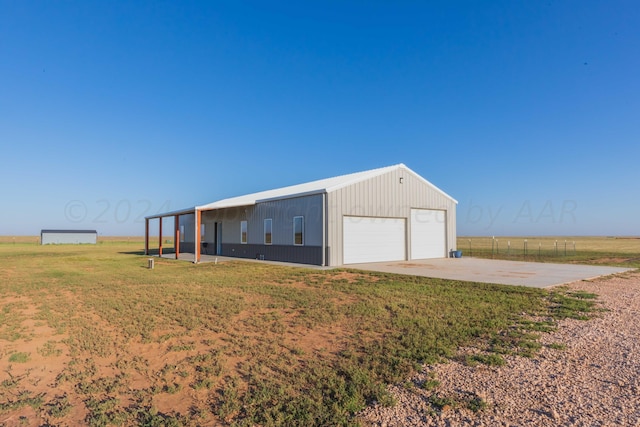 garage with a yard and a rural view