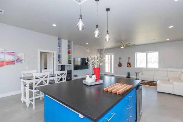 kitchen with concrete floors, wine cooler, a kitchen island, blue cabinetry, and ceiling fan