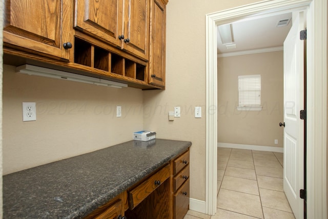 kitchen with visible vents, baseboards, crown molding, brown cabinetry, and light tile patterned flooring