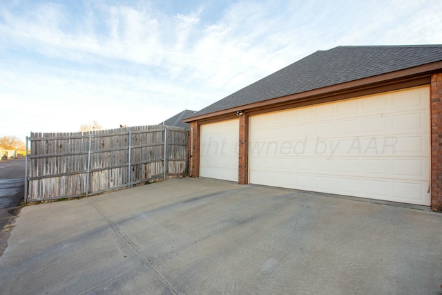 garage with fence and concrete driveway