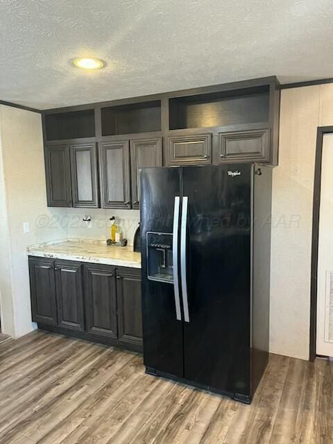 kitchen with wood-type flooring, black fridge, and a textured ceiling