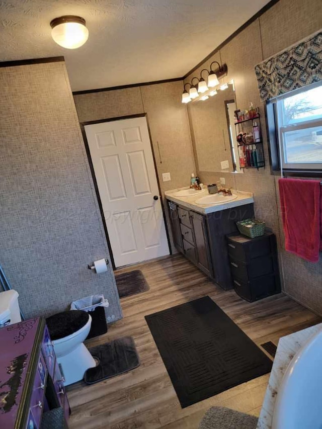 bathroom with hardwood / wood-style flooring, vanity, toilet, crown molding, and a textured ceiling