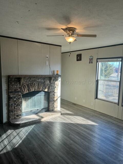 unfurnished living room with ceiling fan, a stone fireplace, a textured ceiling, and light wood-type flooring