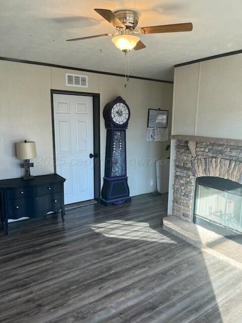 unfurnished living room featuring dark hardwood / wood-style flooring, crown molding, a fireplace, and ceiling fan