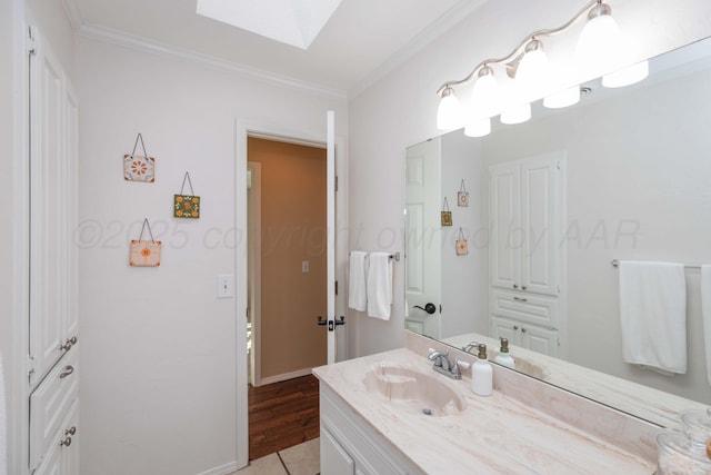 bathroom with vanity, ornamental molding, a skylight, tile patterned floors, and baseboards