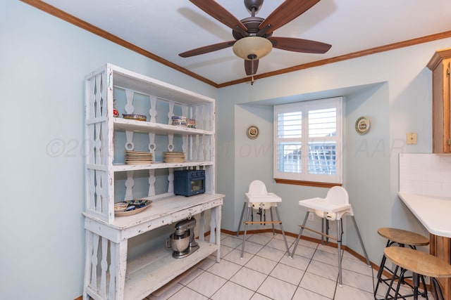 home office featuring light tile patterned floors, ceiling fan, ornamental molding, and baseboards