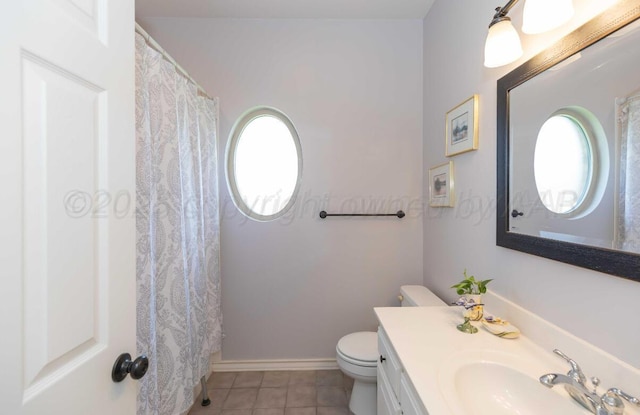 bathroom featuring toilet, tile patterned flooring, healthy amount of natural light, and vanity