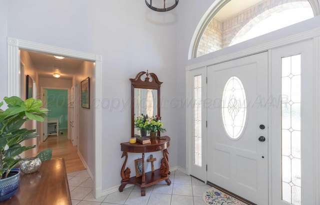 entrance foyer with light tile patterned floors, a high ceiling, baseboards, and plenty of natural light