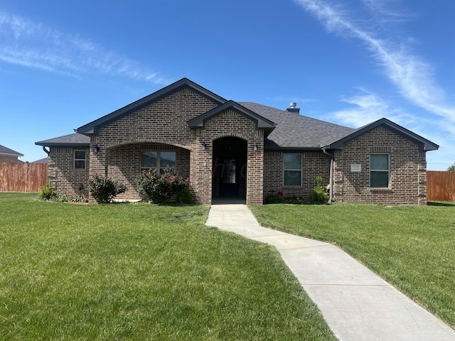 1712 NE 6th St, Dumas, TX 79020 - view of front of house featuring brick siding, roof with shingles, and a chimney