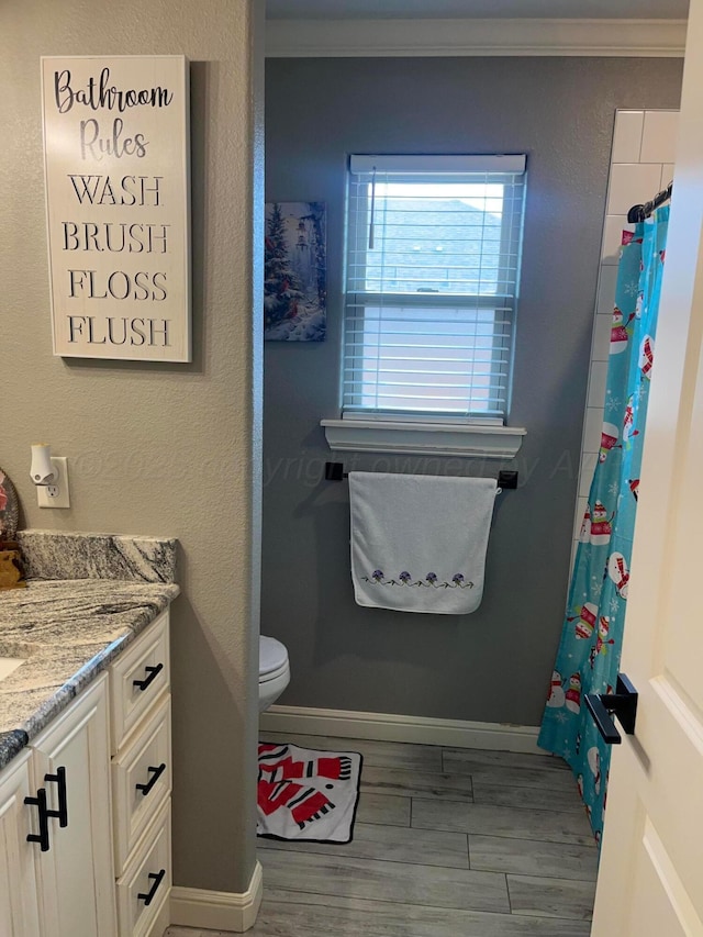 1712 NE 6th St, Dumas, TX 79020 - bathroom with vanity, ornamental molding, wood finished floors, and a shower with curtain