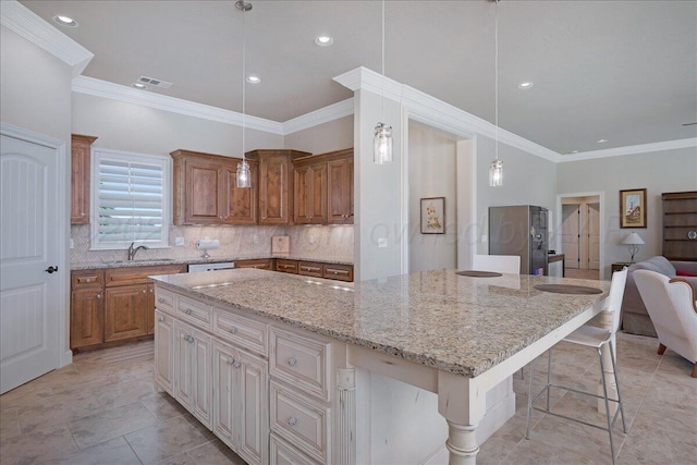 19550 Saddlehorn Rd, Amarillo, TX 79119 - kitchen featuring a sink, open floor plan, crown molding, light stone counters, and a kitchen bar