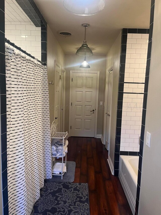 hall featuring baseboards, visible vents, and wood finished floors