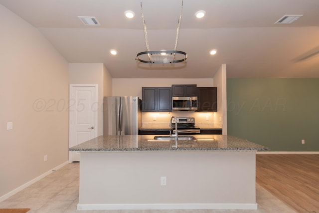 kitchen featuring visible vents, a sink, baseboards, and stainless steel appliances