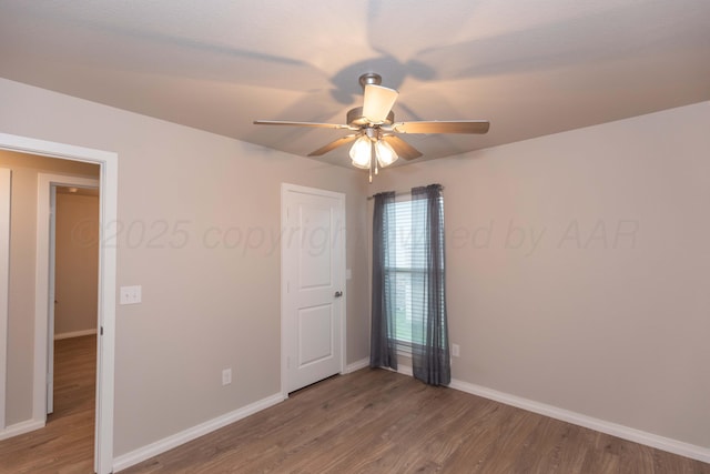 spare room with baseboards, ceiling fan, and wood finished floors