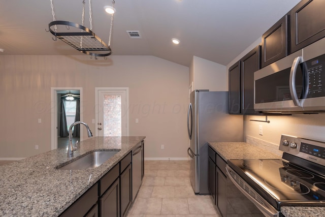 kitchen featuring visible vents, light stone counters, a sink, appliances with stainless steel finishes, and vaulted ceiling