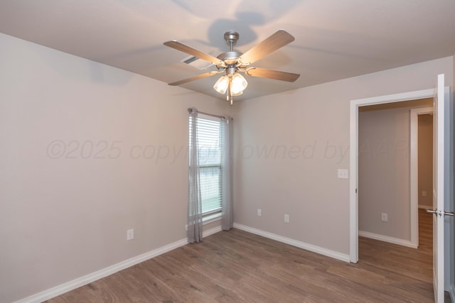 spare room with baseboards, ceiling fan, and wood finished floors