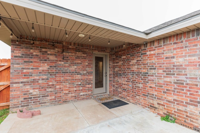 doorway to property featuring brick siding and a patio