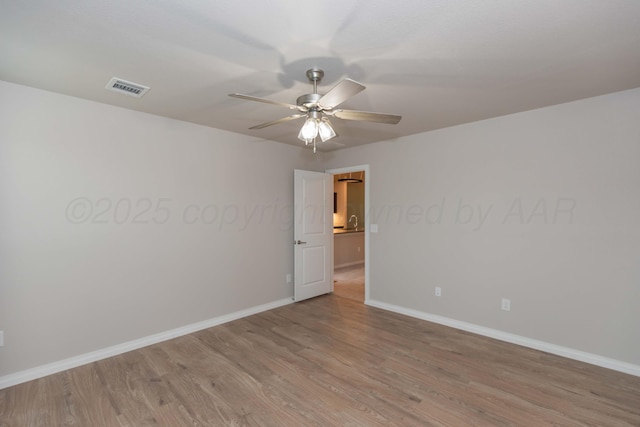 empty room with a ceiling fan, baseboards, visible vents, and light wood-style flooring