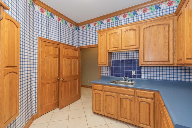 kitchen with tasteful backsplash, crown molding, sink, and light tile patterned floors