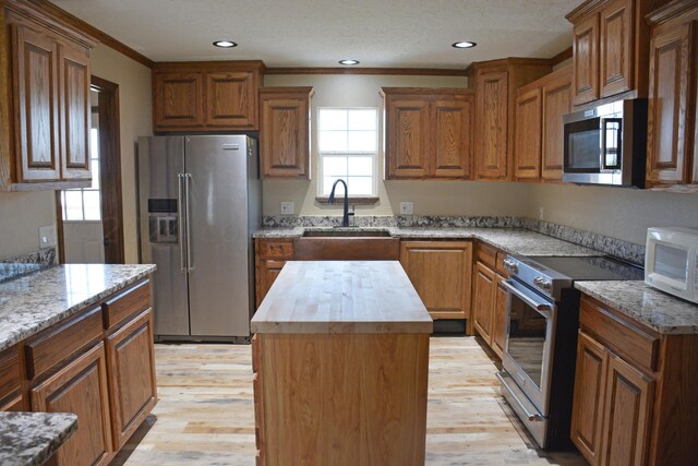 kitchen with light hardwood / wood-style floors, sink, a kitchen island, wood counters, and appliances with stainless steel finishes