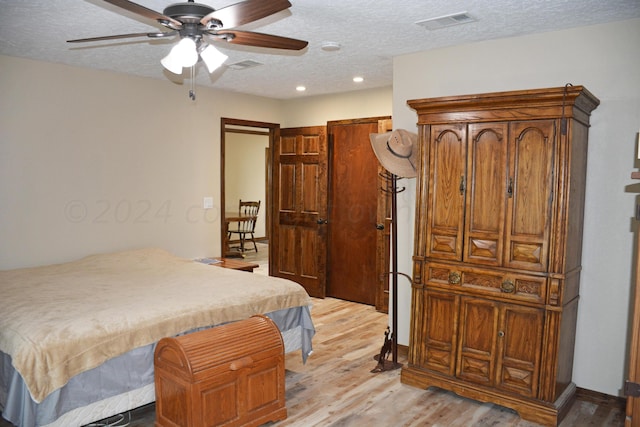 bedroom with light hardwood / wood-style floors, ceiling fan, and a textured ceiling