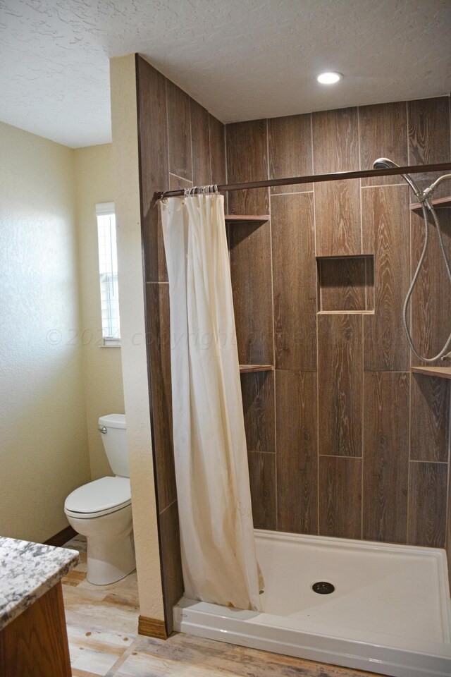 bathroom with wood-type flooring, toilet, a textured ceiling, vanity, and a shower with shower curtain