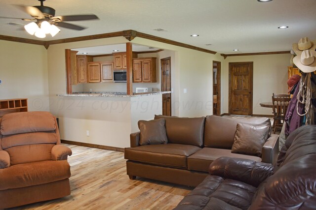 living room featuring ornamental molding, light wood-type flooring, and ceiling fan