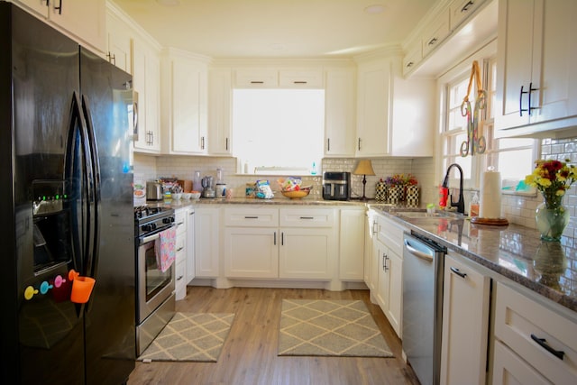 kitchen with stone counters, appliances with stainless steel finishes, sink, and white cabinets