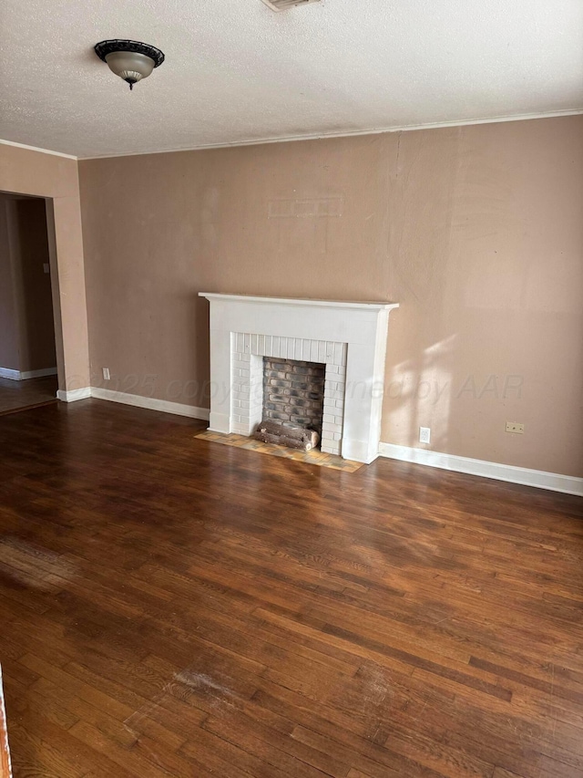 unfurnished living room featuring a textured ceiling, a brick fireplace, wood finished floors, and baseboards