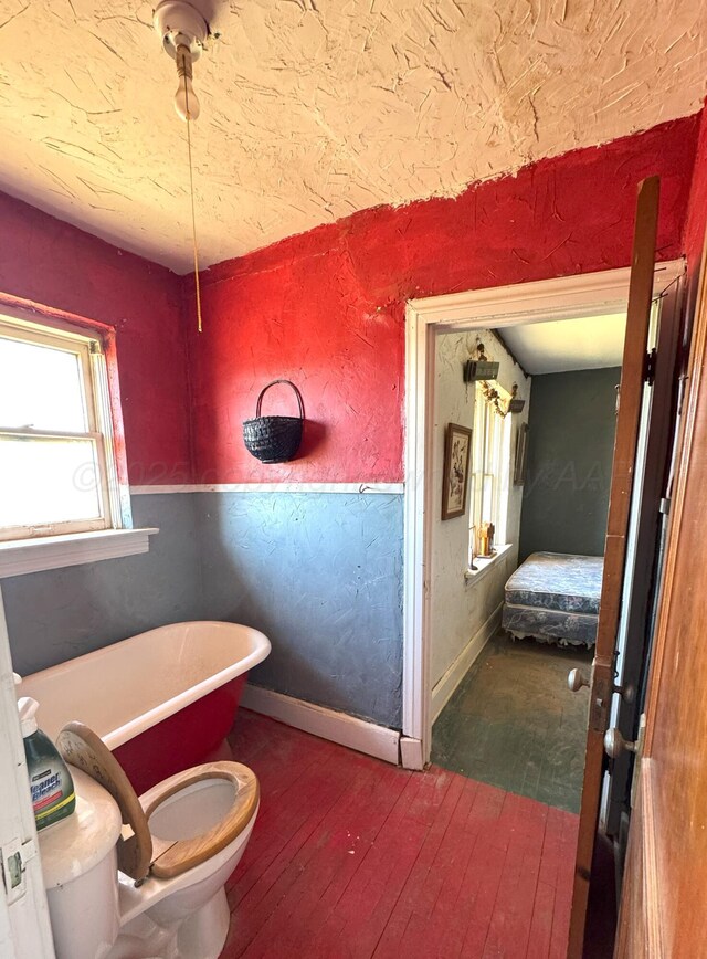 bathroom with toilet, a bathtub, and hardwood / wood-style floors