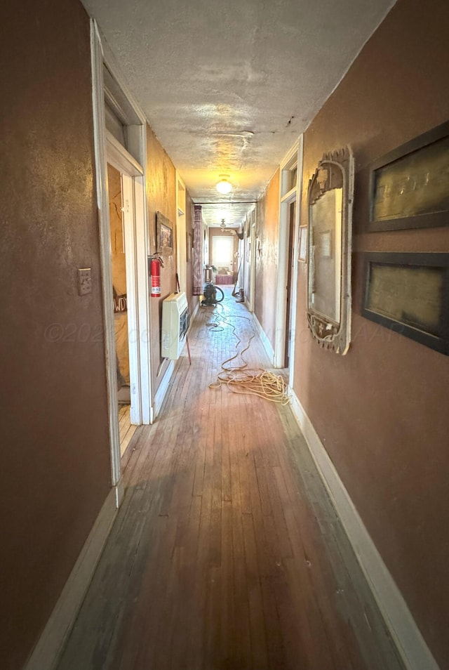 hall featuring heating unit, a textured ceiling, and hardwood / wood-style floors