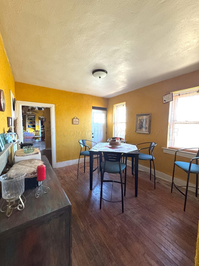 dining space with plenty of natural light, a textured ceiling, and dark hardwood / wood-style flooring