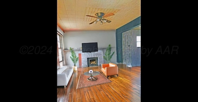 living room with dark hardwood / wood-style floors, ceiling fan, and a brick fireplace