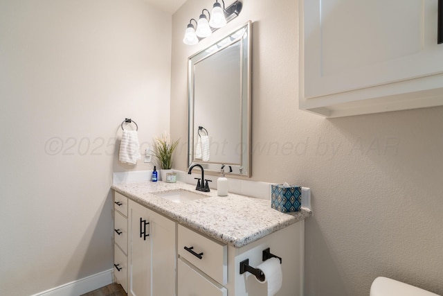 bathroom featuring baseboards, toilet, and vanity