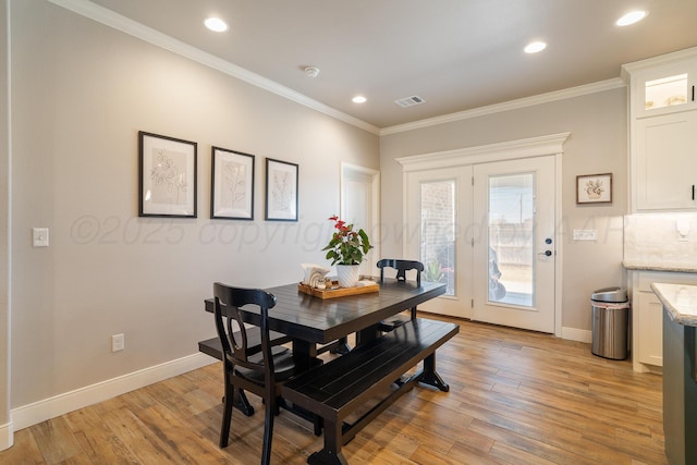 dining area with light wood-style flooring, baseboards, visible vents, and ornamental molding