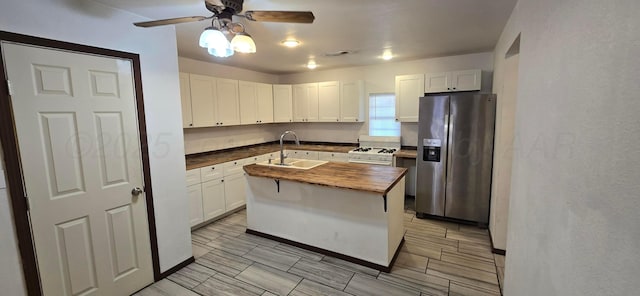 kitchen with white cabinets, sink, stainless steel refrigerator with ice dispenser, butcher block countertops, and a kitchen island