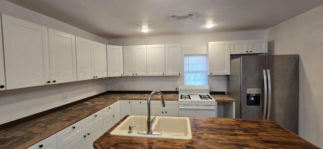 kitchen with white range, white cabinetry, sink, and stainless steel refrigerator with ice dispenser