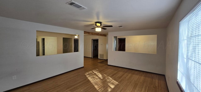 empty room with ceiling fan, a healthy amount of sunlight, and wood-type flooring