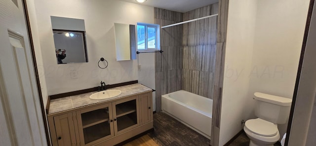 full bathroom featuring hardwood / wood-style floors, vanity, toilet, and tiled shower / bath