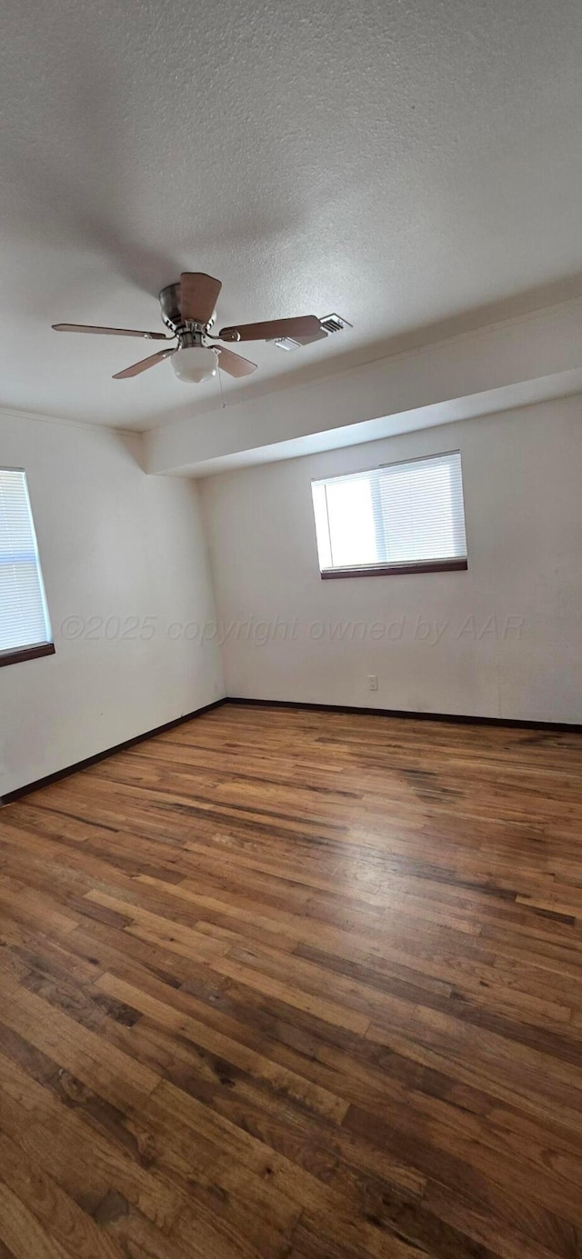 empty room featuring ceiling fan, dark hardwood / wood-style flooring, and a textured ceiling