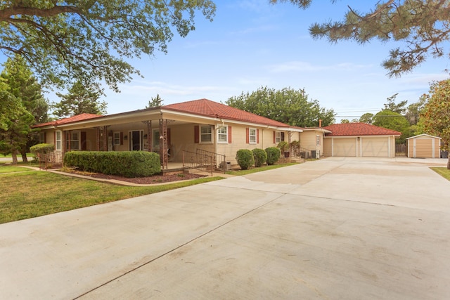 single story home with an outdoor structure, concrete driveway, a front lawn, a porch, and a garage