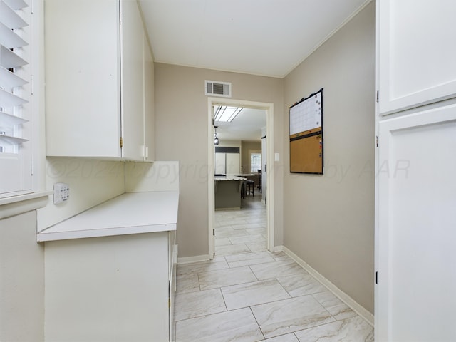hallway featuring marble finish floor, baseboards, and visible vents