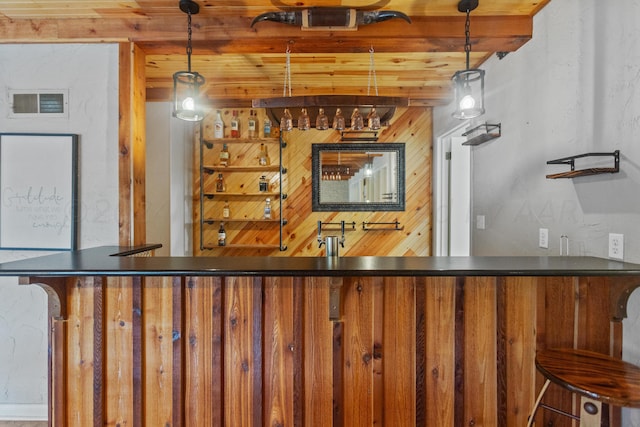 bar featuring hanging light fixtures, beamed ceiling, visible vents, and bar area